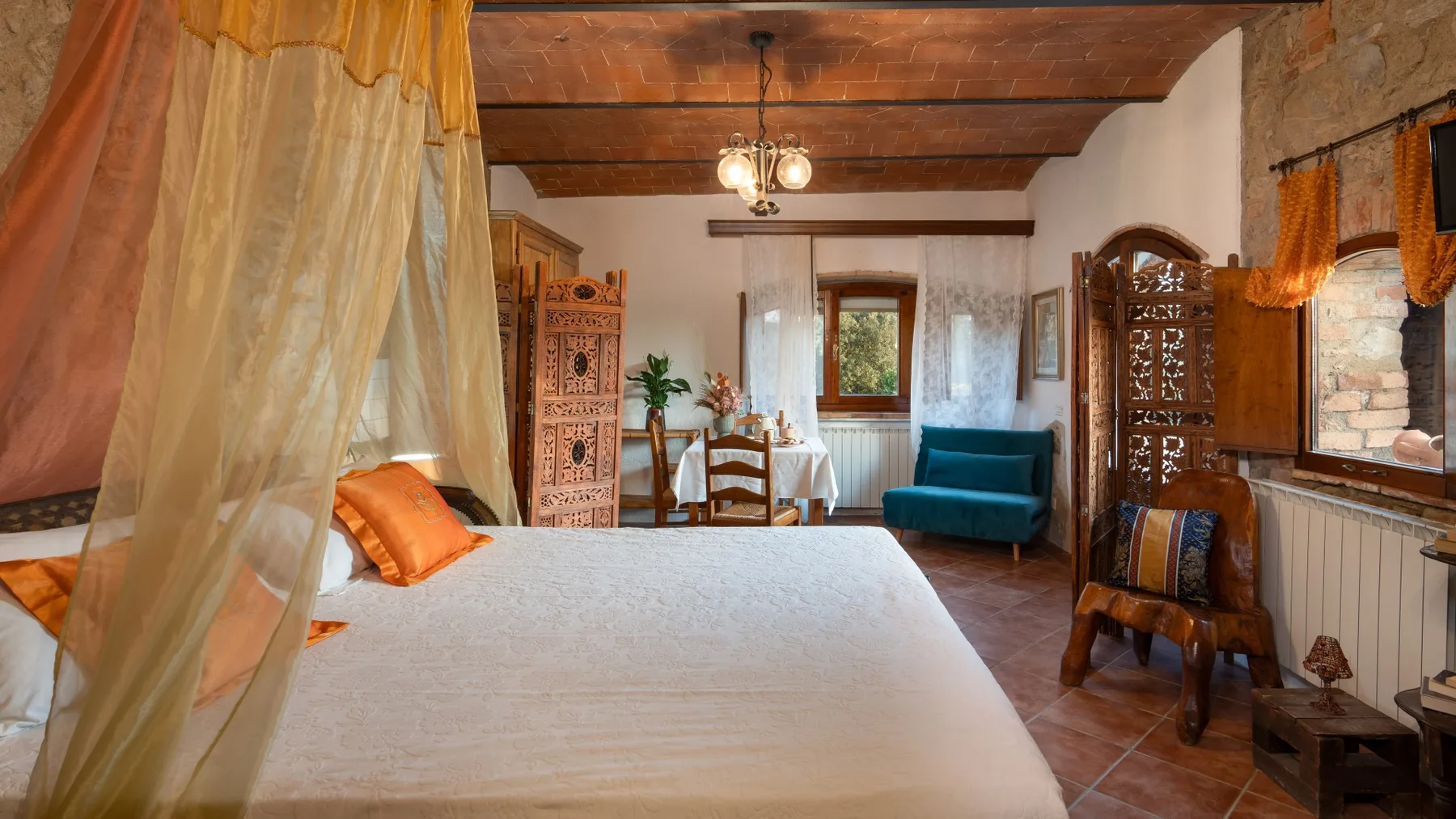 A bedroom with a large bed, a small table, and a blue seat.