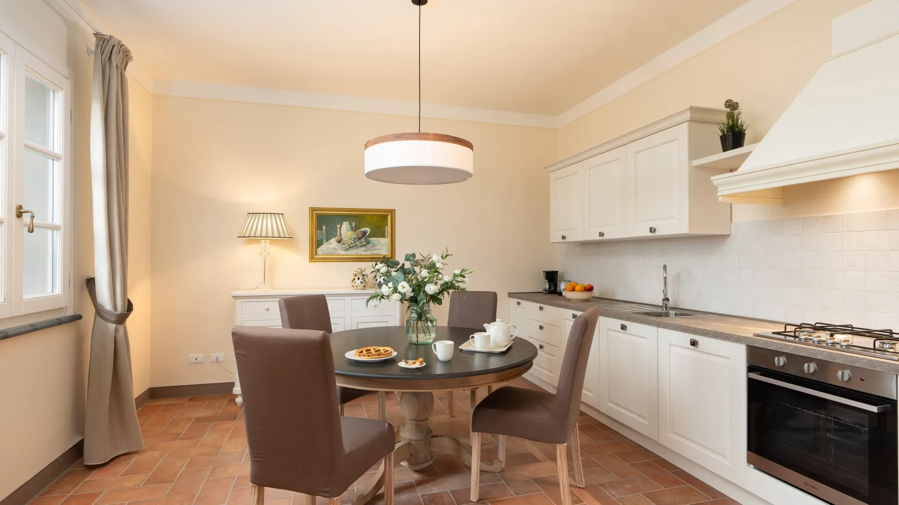 Comedor junto a una cocina, con una mesa redonda y sillas.