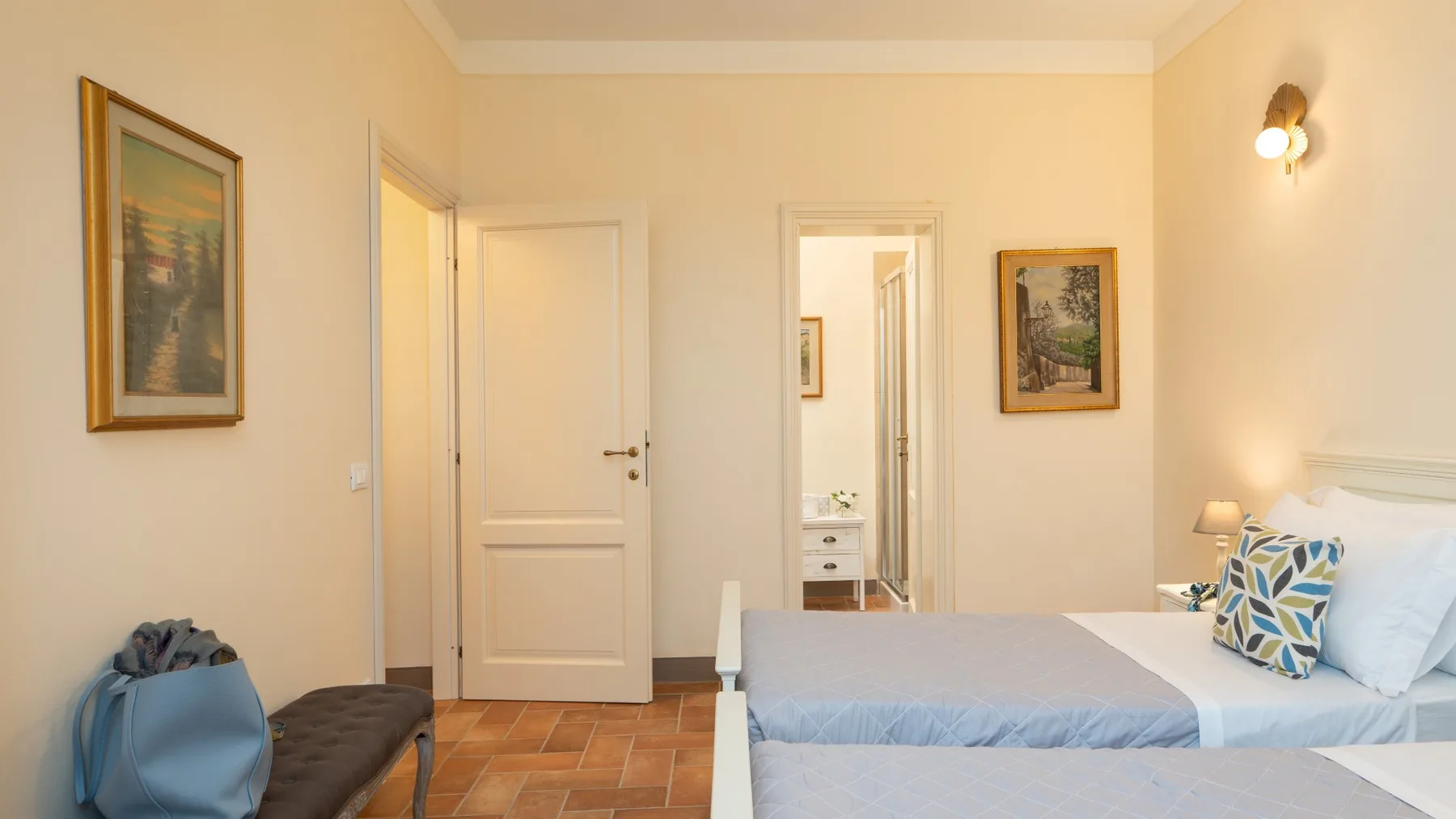 Un dormitorio con una cama arreglada, cuadros enmarcados y una puerta.