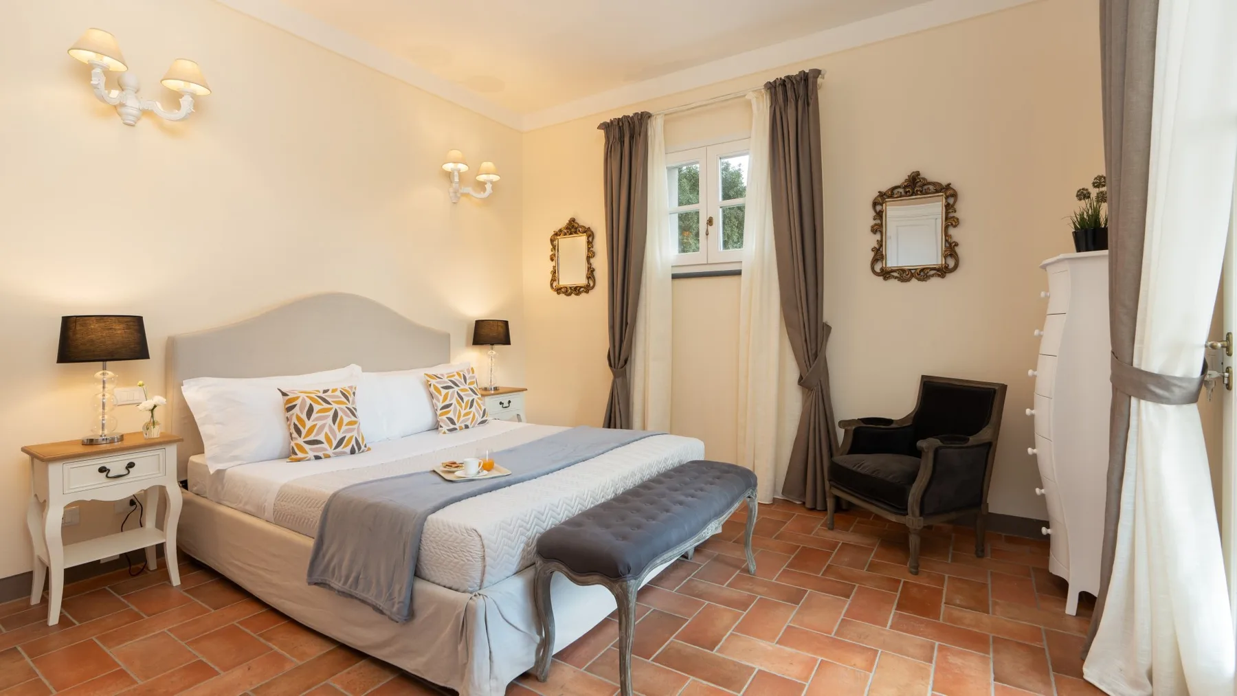 Un dormitorio con una cama tendida, mesitas de noche y una ventana con cortinas.