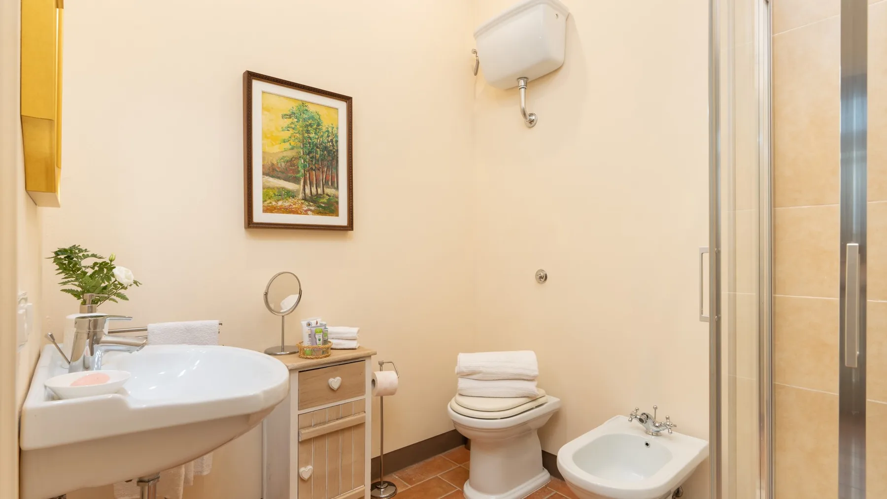 Un baño con lavabo, inodoro y ducha con mampara de vidrio.