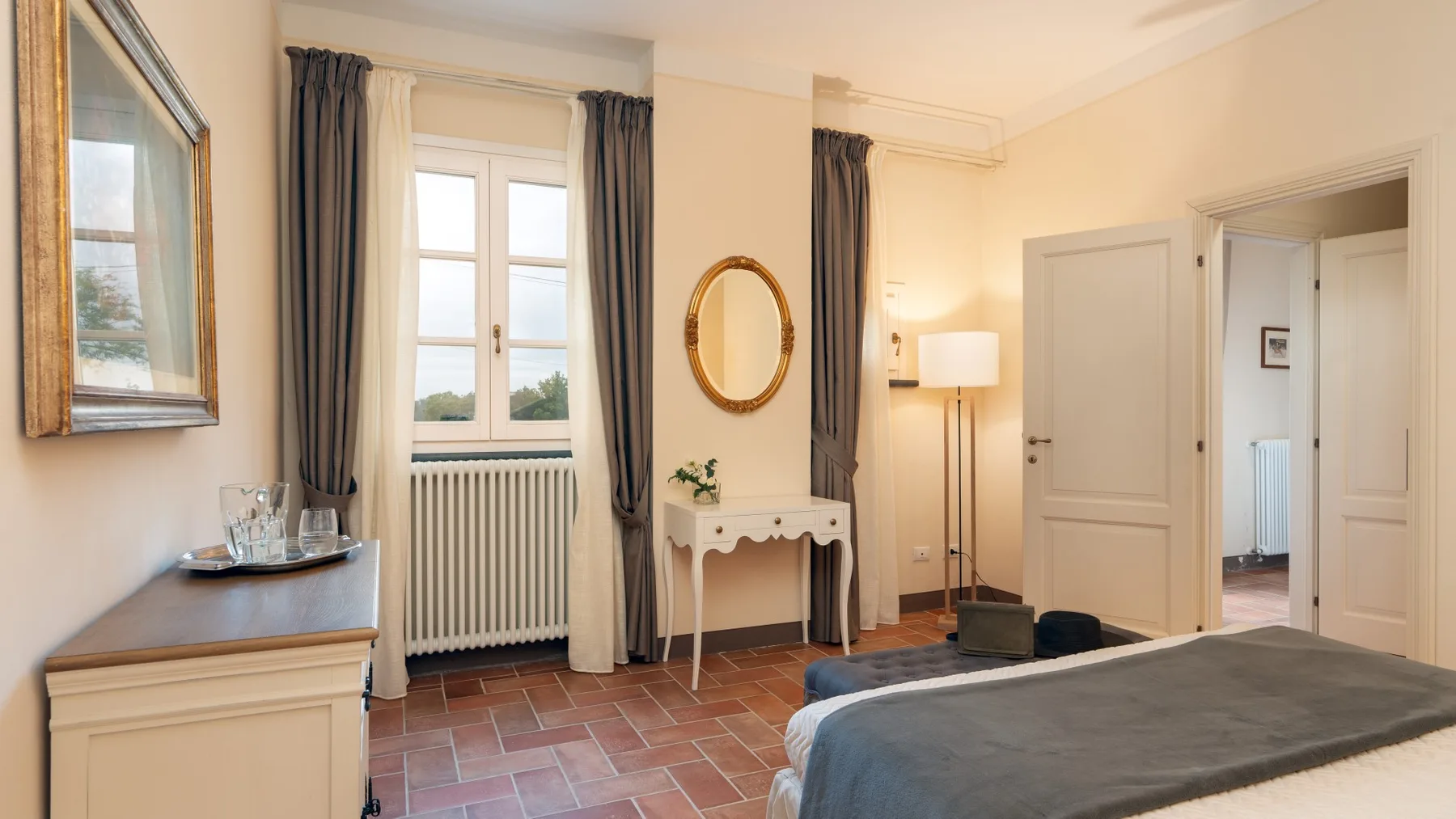 Un dormitorio con una cama, una ventana y una pequeña mesa consola.