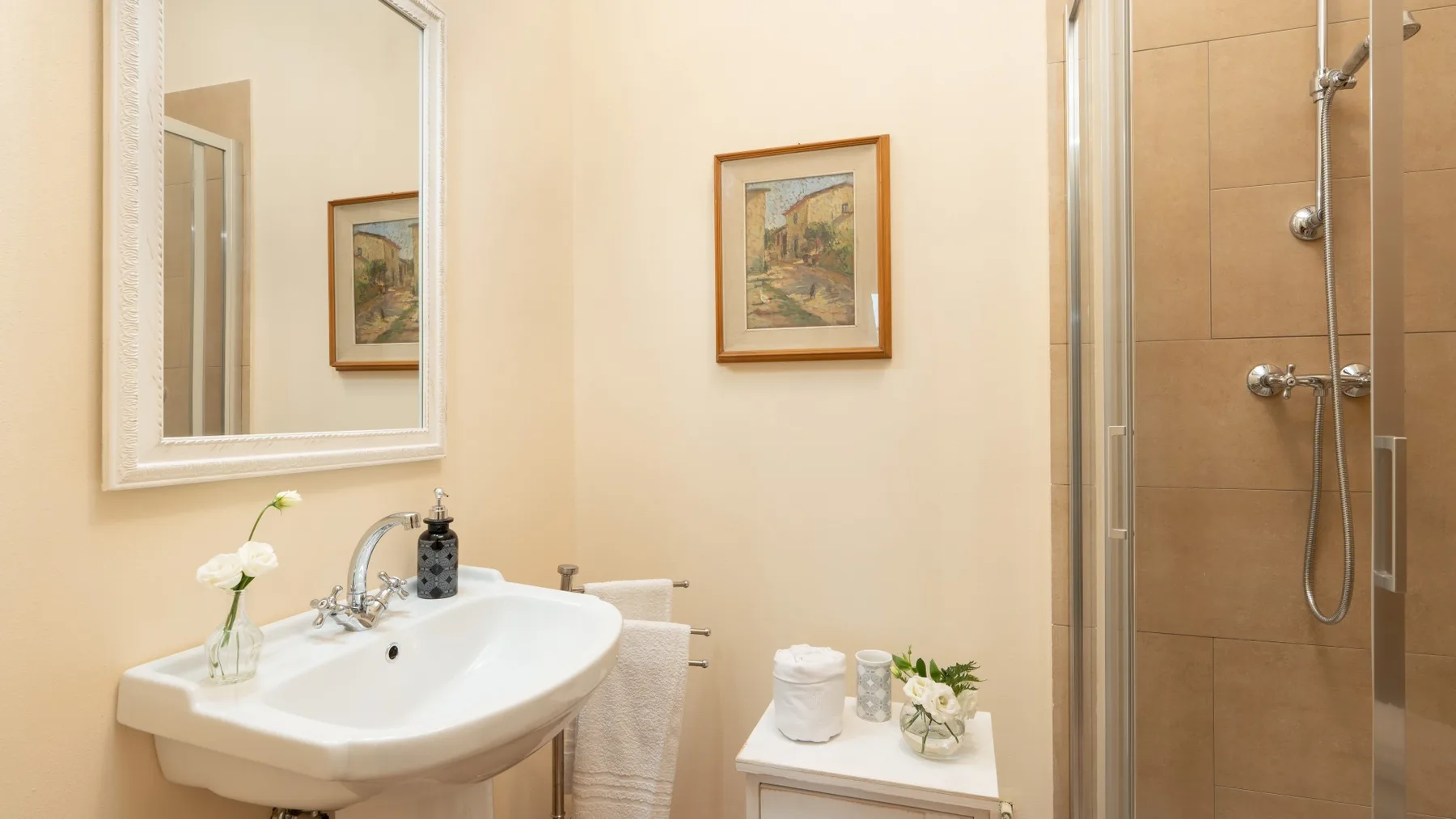 Un baño luminoso con un lavabo de pared y una ducha de vidrio.