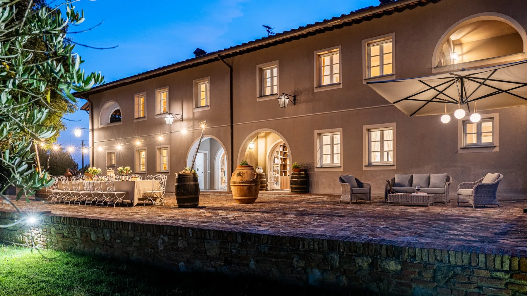 Un edificio iluminado da a un patio pavimentado con asientos al aire libre.