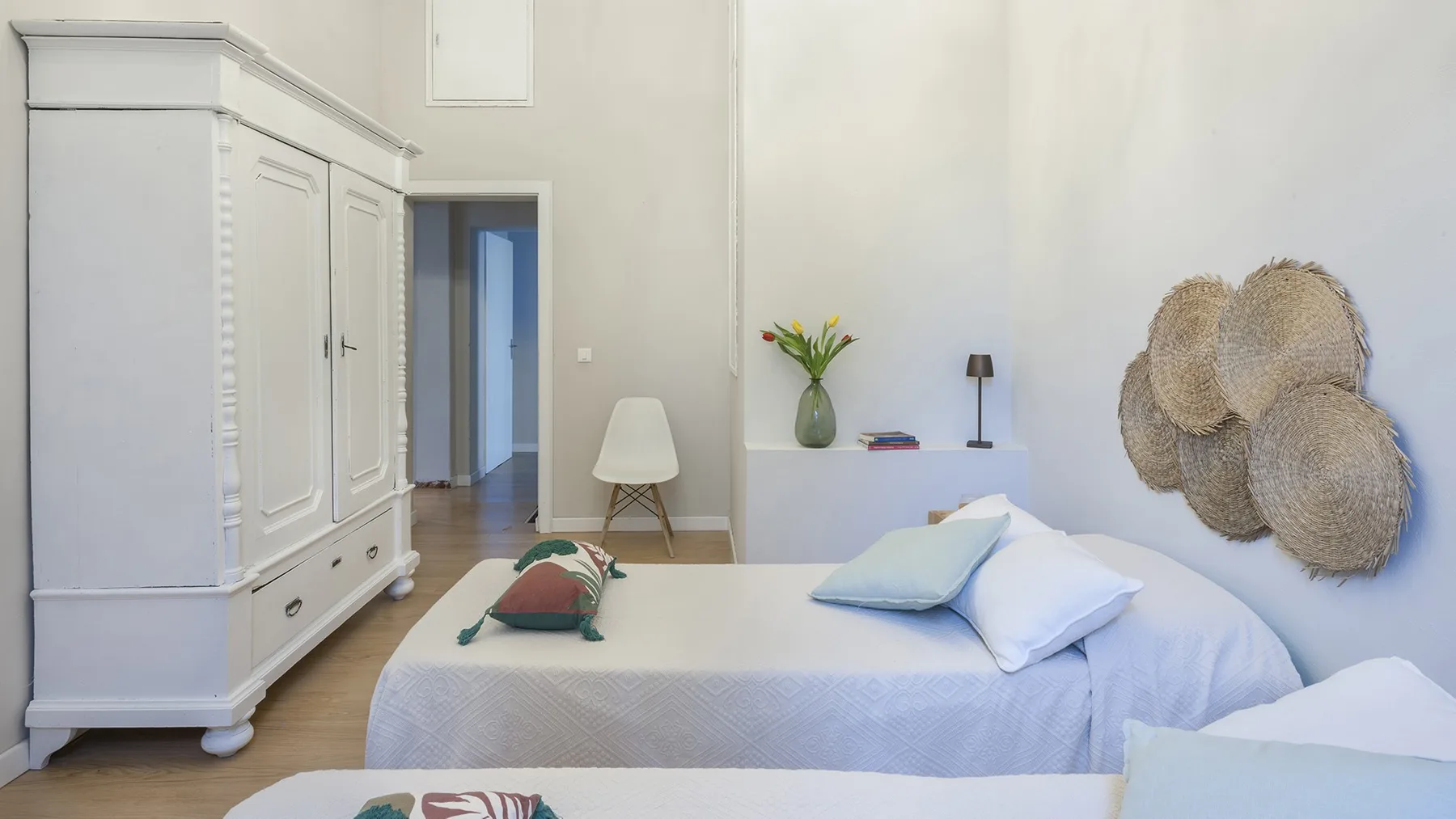A bright bedroom with a white bed and a large wardrobe.
