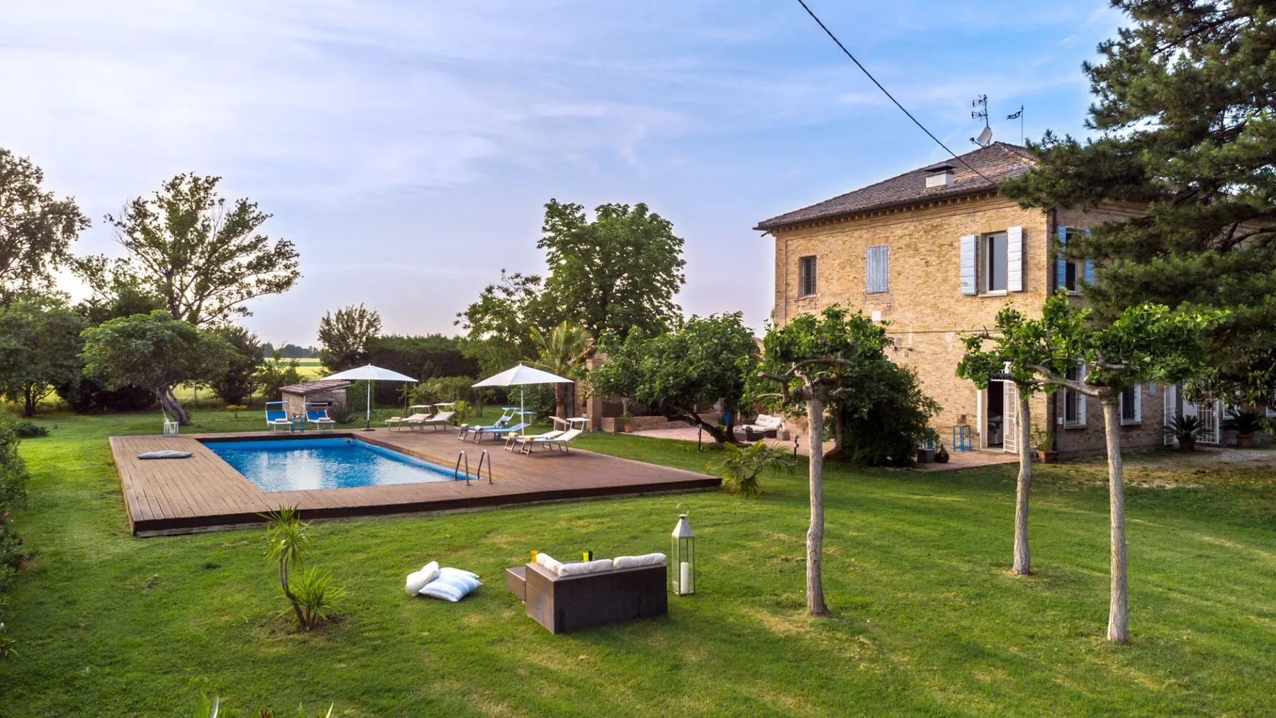 A landscaped yard with a swimming pool and a stone house.