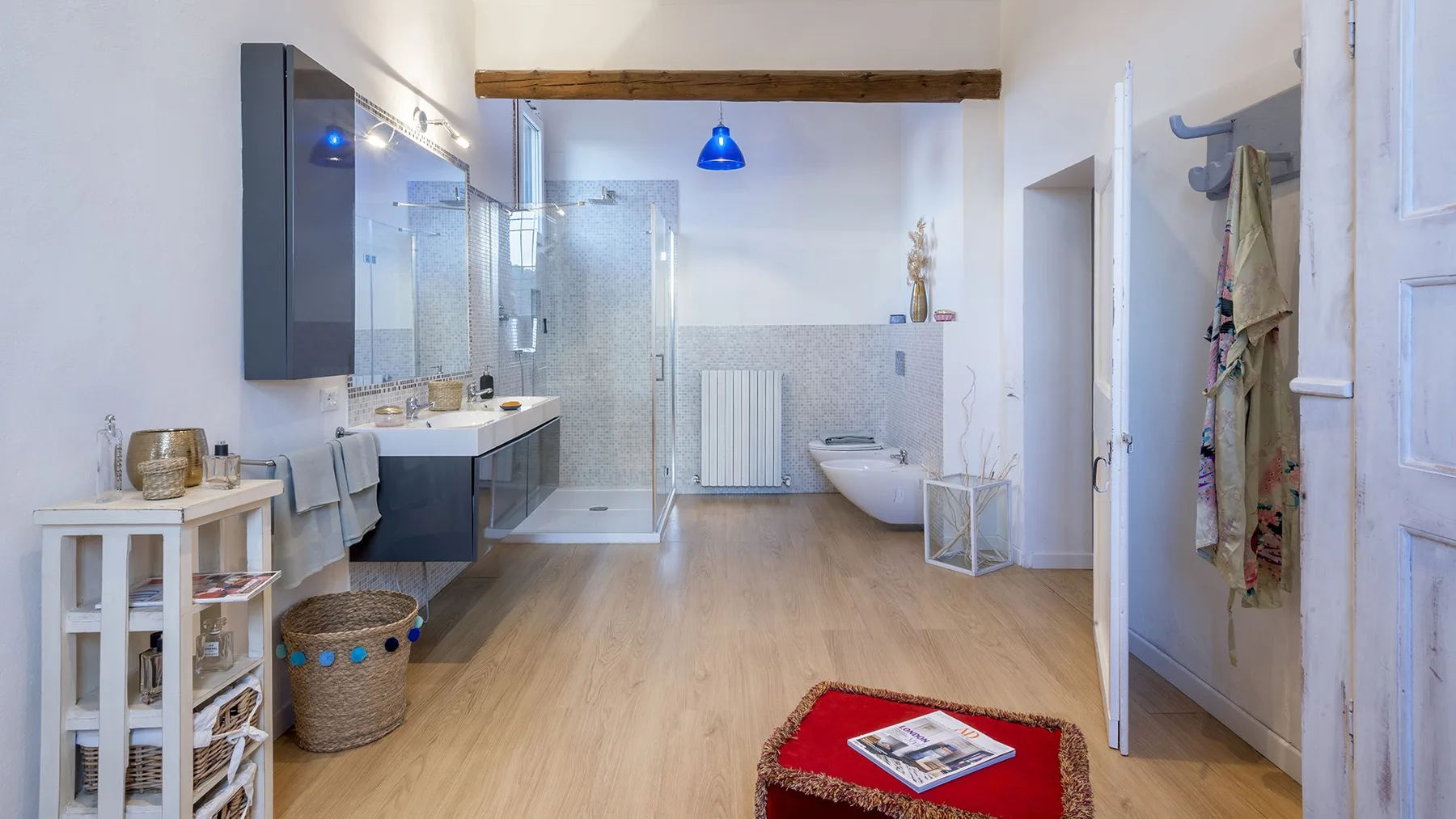A spacious bathroom with a glass shower, bathtub, and blue pendant light.