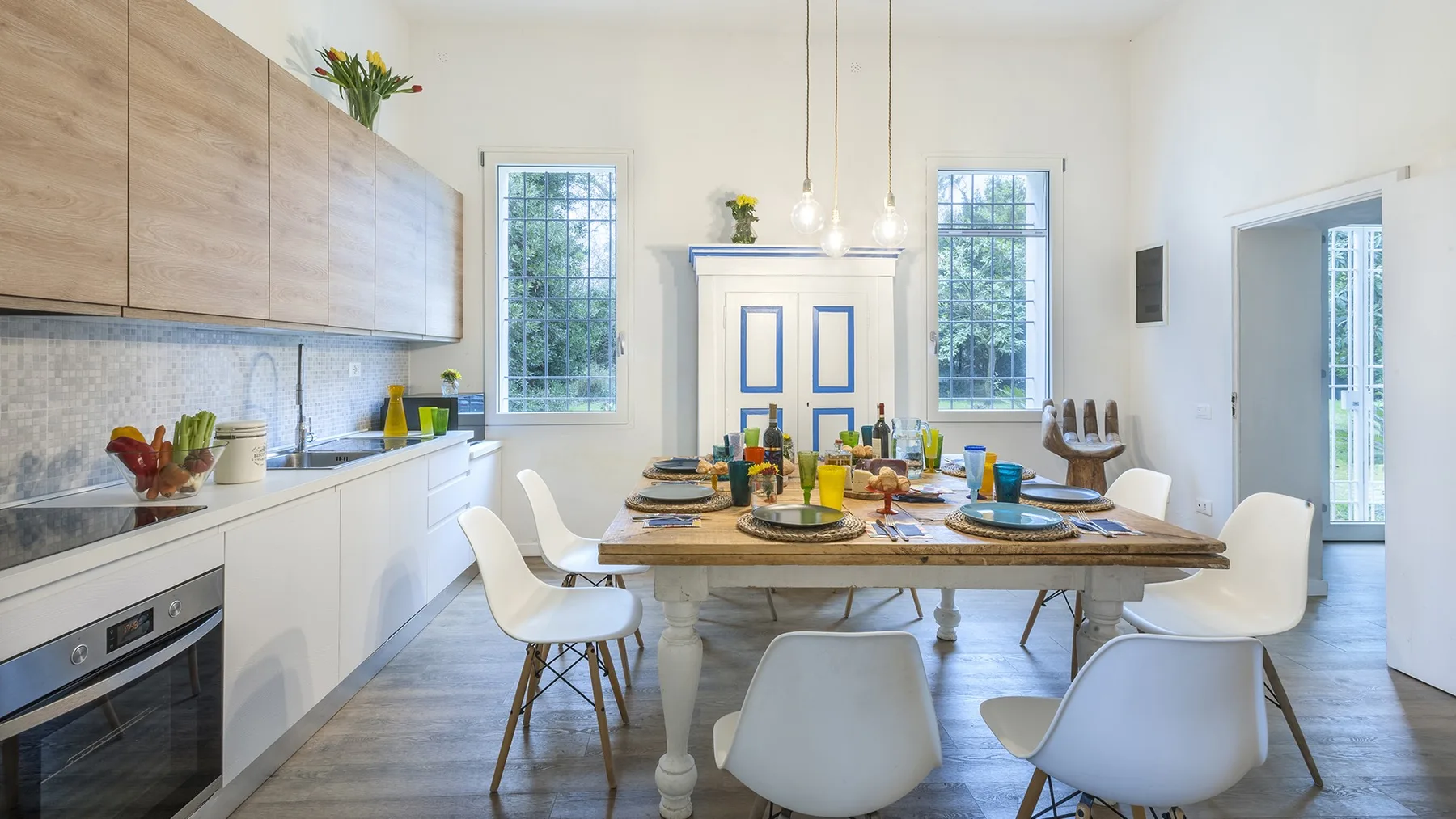 A bright kitchen and dining area with a long table set for a meal.