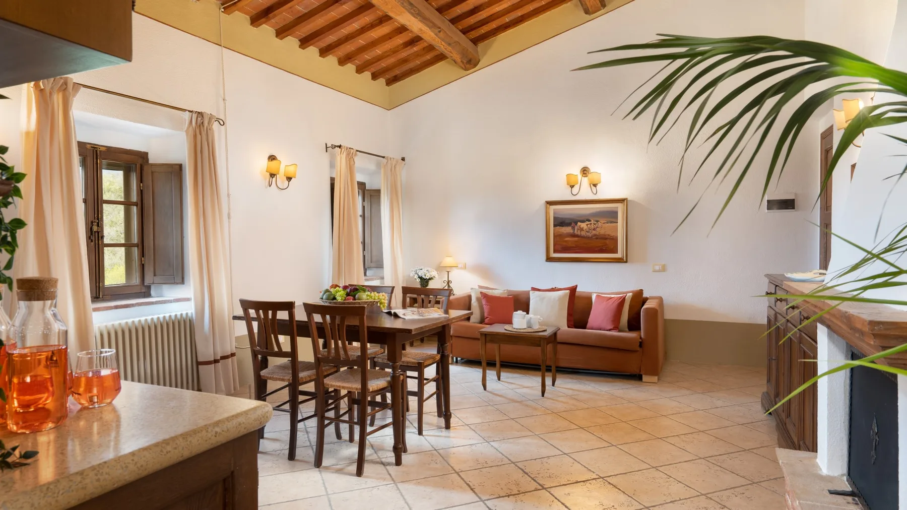 Una zona de estar y comedor con una mesa, asientos y vigas de madera expuestas.