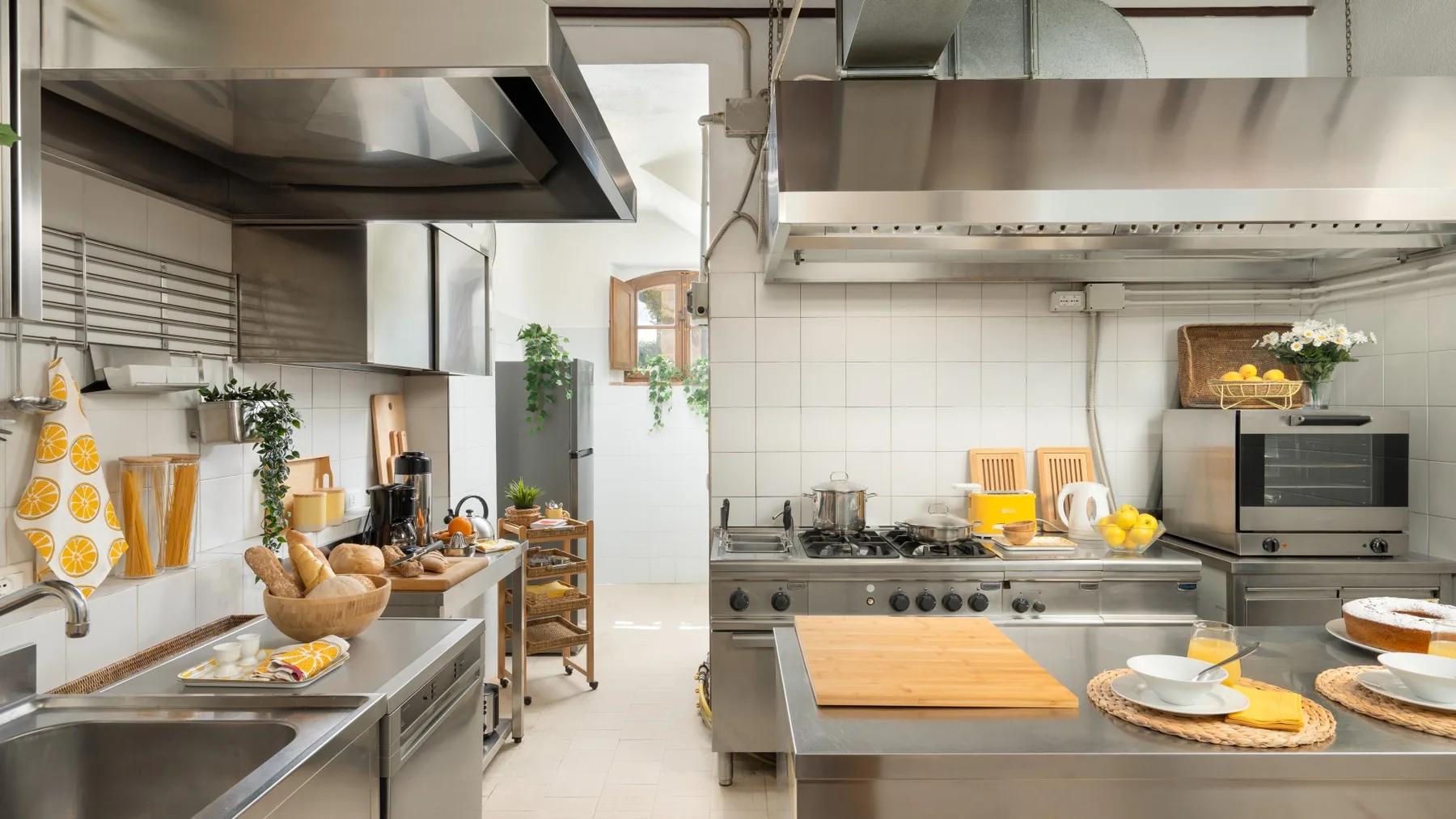 Una cocina luminosa con encimeras de acero inoxidable y electrodomésticos de cocina.