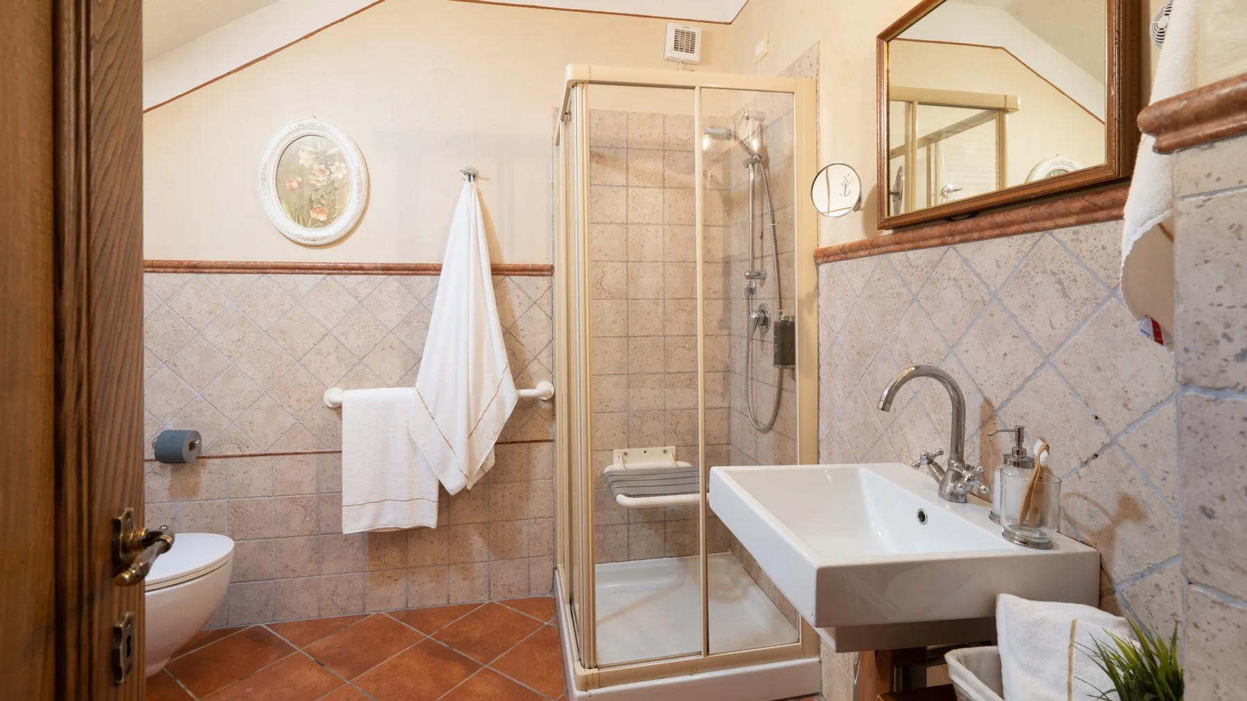 Un baño con azulejos, ducha, lavabo e inodoro.