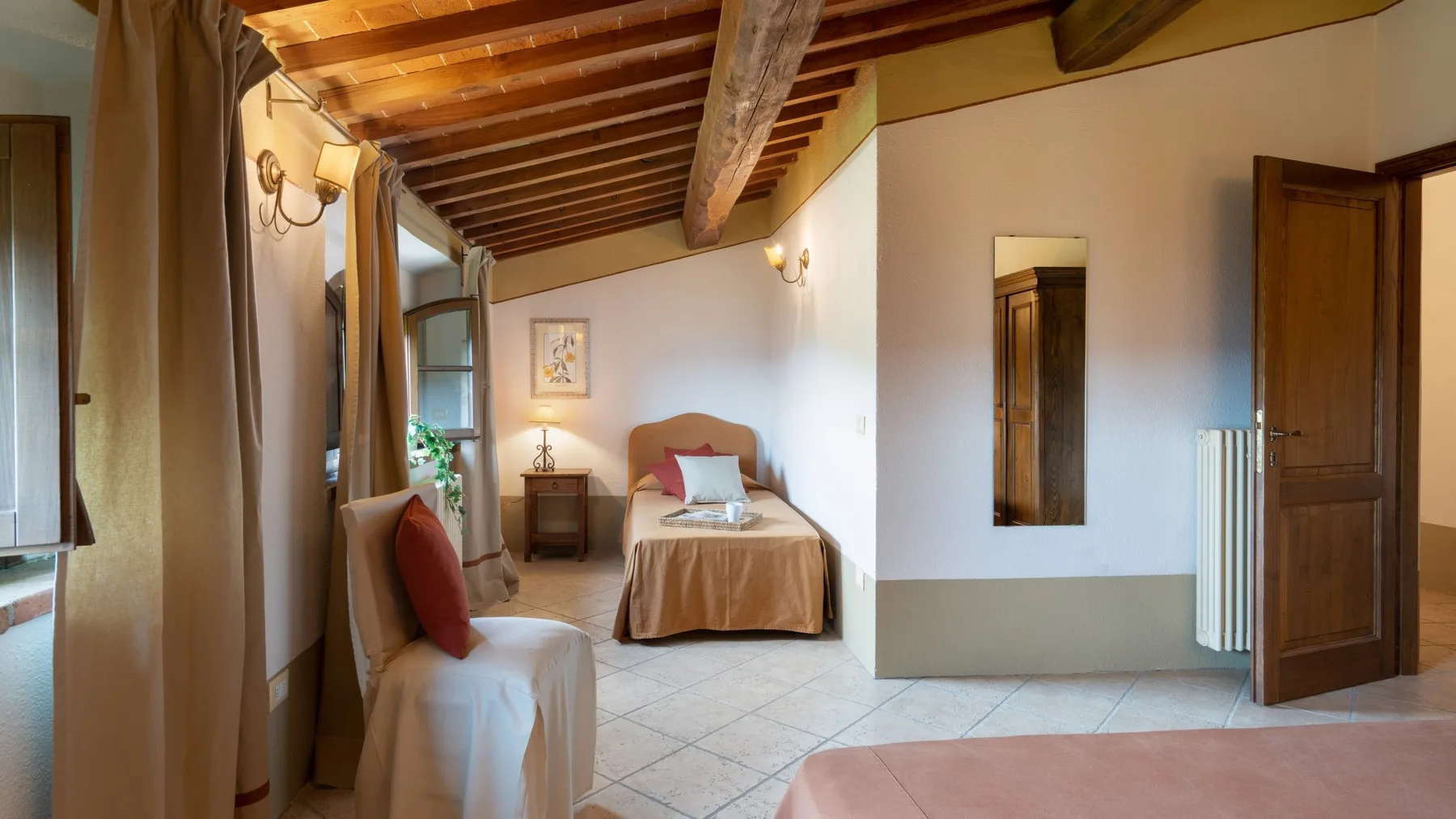 Dormitorio con una cama, asientos y vigas de madera a la vista.