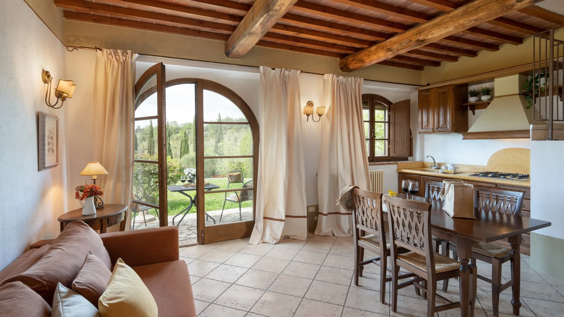 Un comedor y una cocina se abren al jardín a través de altas puertas acristaladas arqueadas.