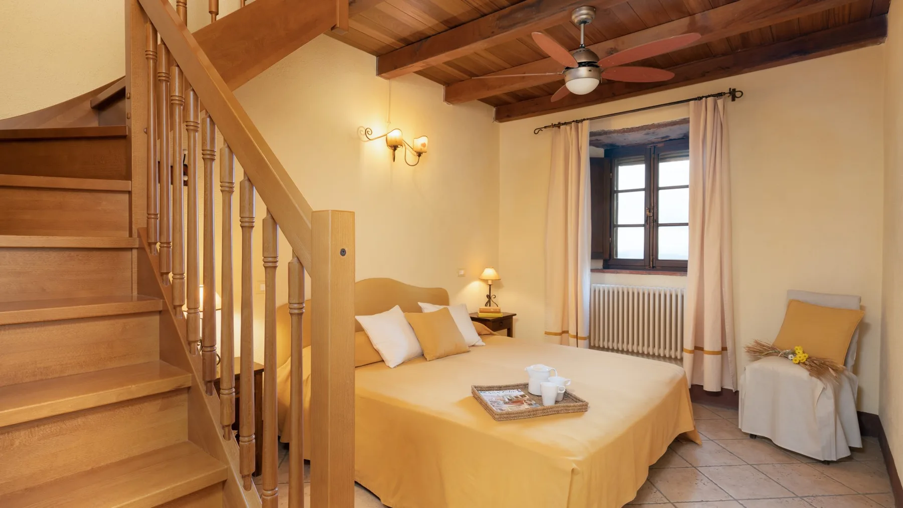 Un dormitorio con una cama, una escalera de madera y una ventana.