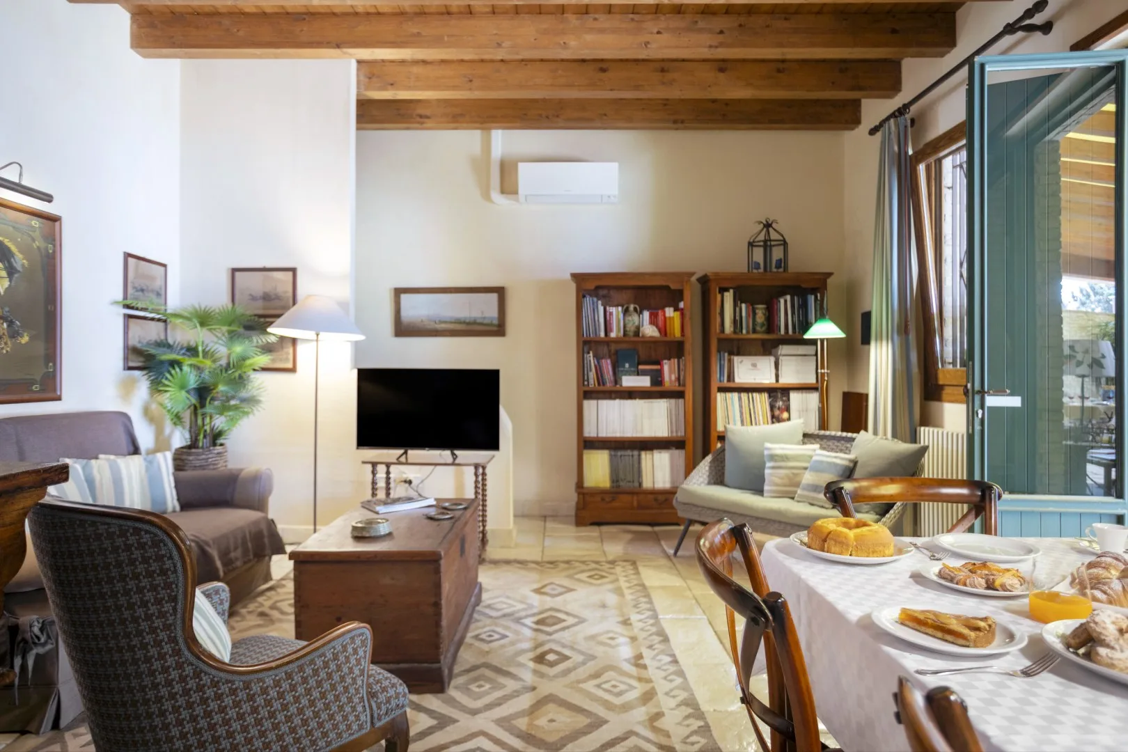 Una sala de estar y comedor con asientos, estanterías y una mesa puesta.