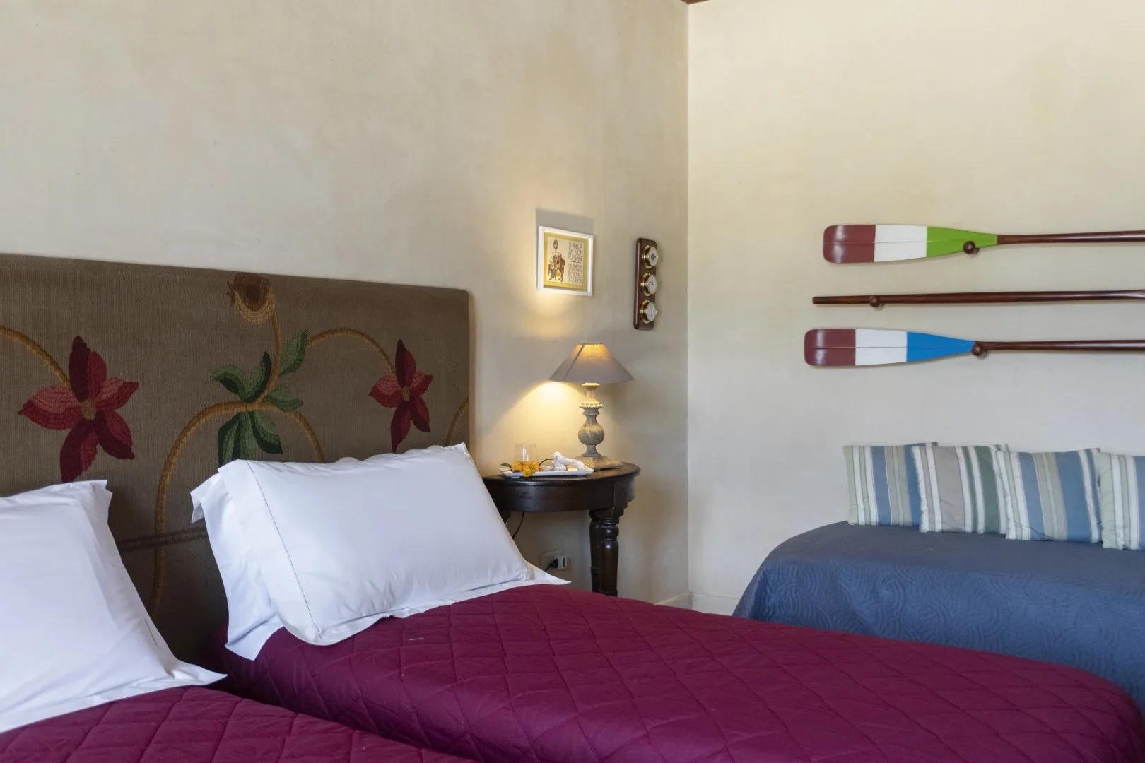 Un dormitorio con dos camas, una mesa de noche y remos decorativos en la pared.