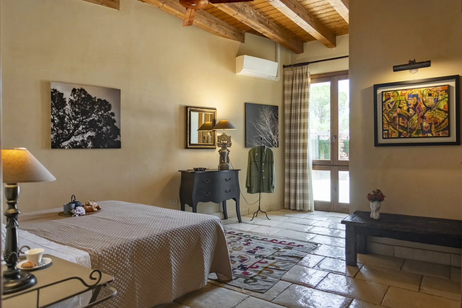 Un dormitorio con una cama, cuadros y vigas de madera a la vista.