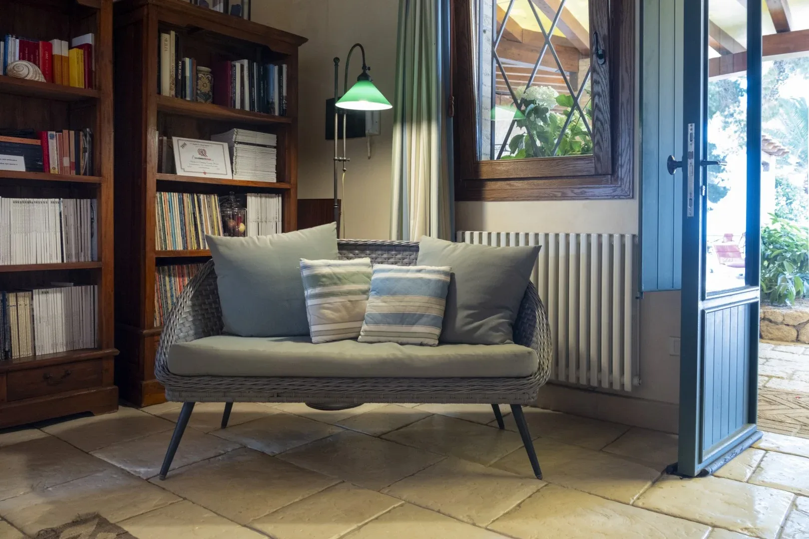Una zona de estar con un asiento acolchado junto a estanterías y una puerta abierta.