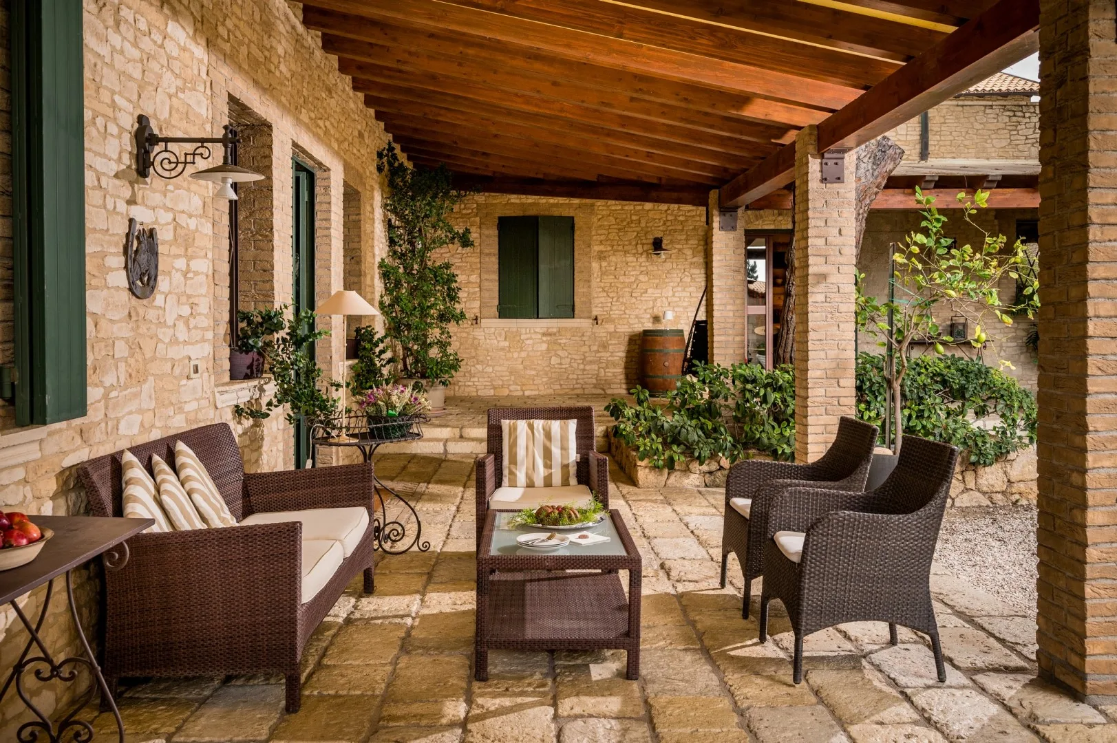 Un patio cubierto con suelo de piedra, asientos y plantas en macetas.