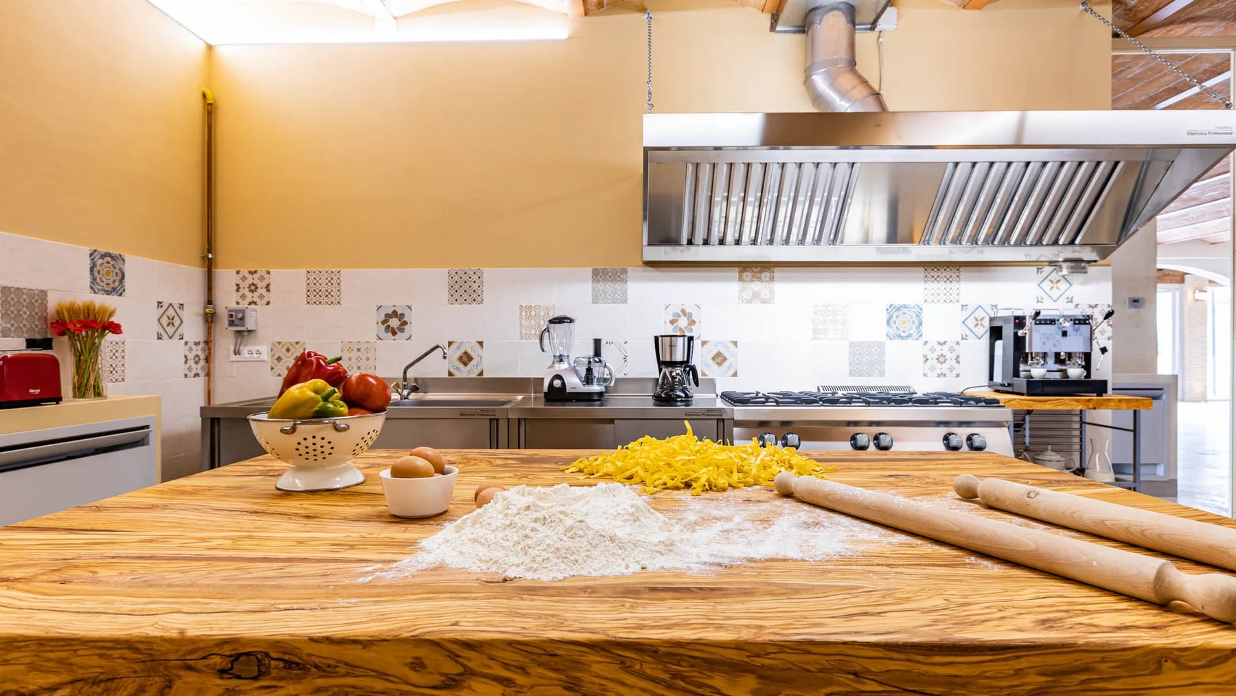 A spacious kitchen with a large wooden worktable and cooking equipment.