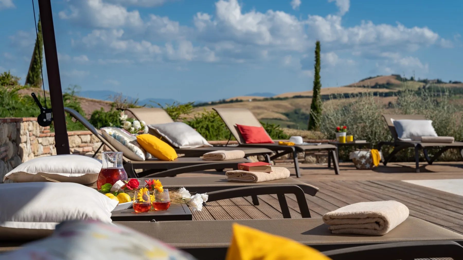 An outdoor terrace has cushioned seating and a view of rolling hills.