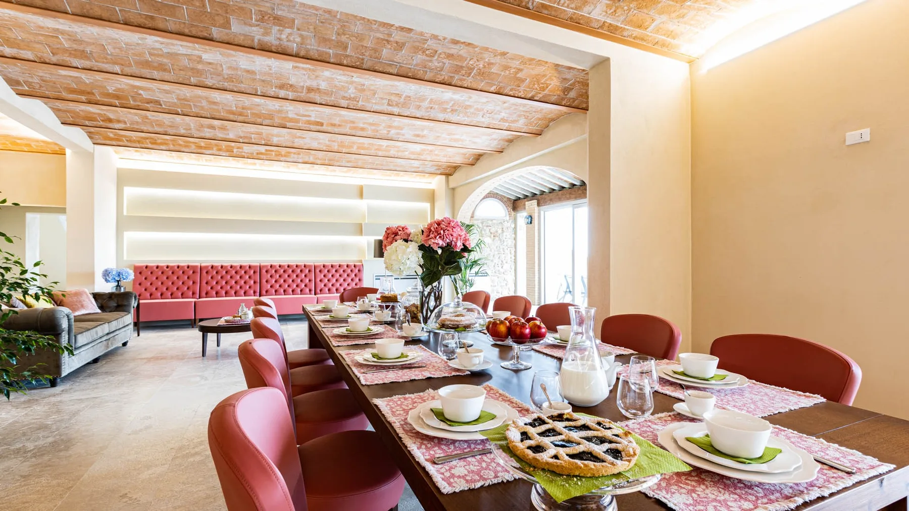 A dining area with a long table set with dishes and flowers.