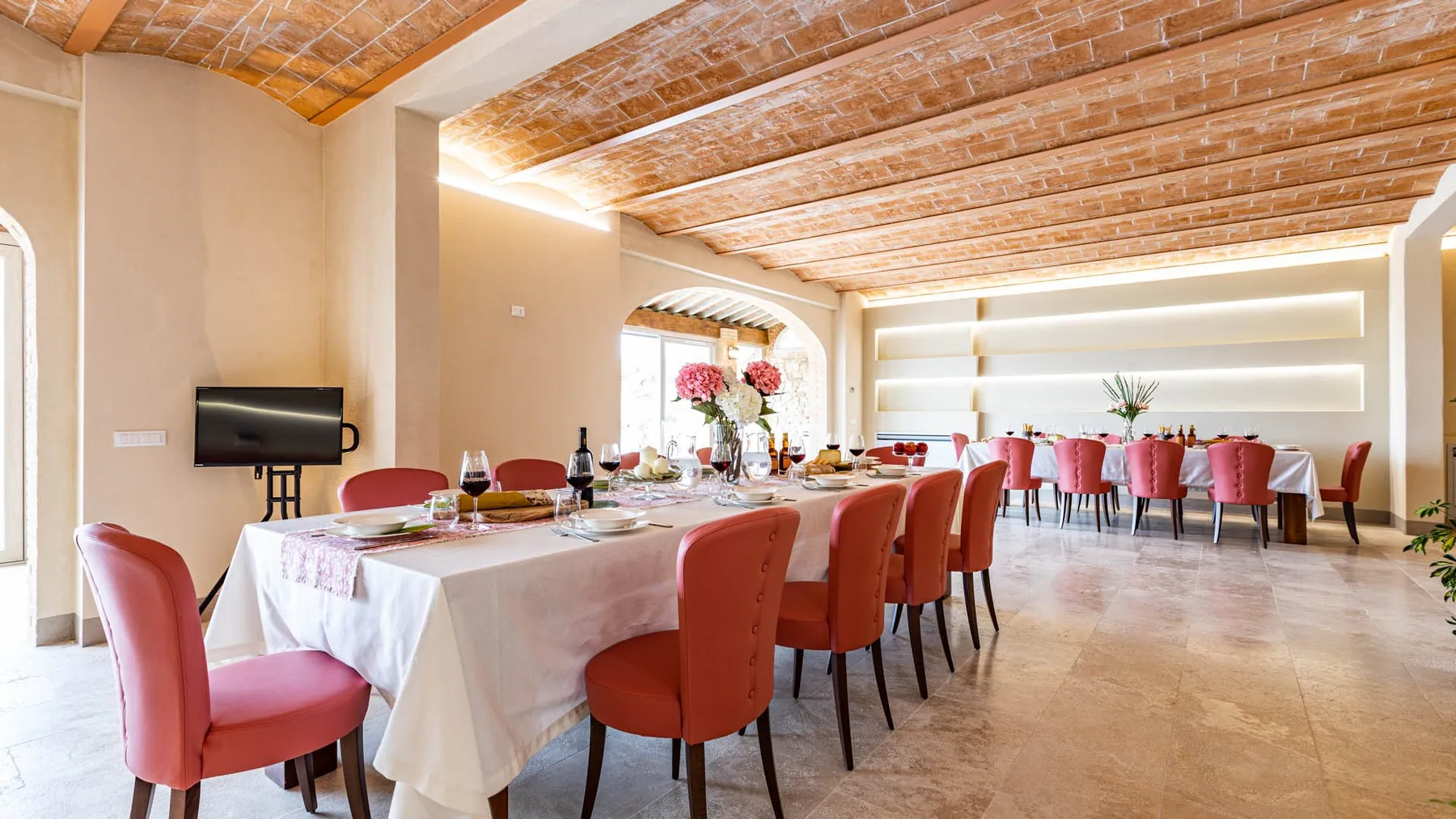 A dining room with long tables set beneath exposed wooden ceiling beams.