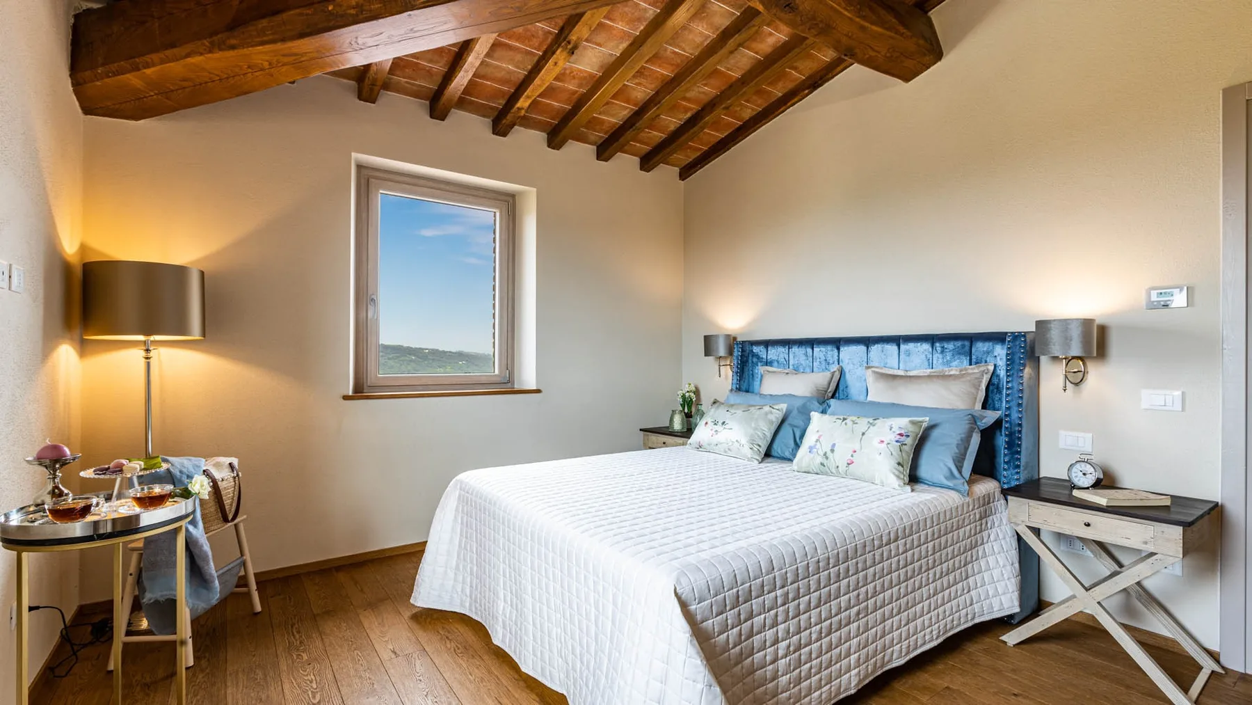 A bedroom with a neatly made bed and exposed wooden ceiling beams.