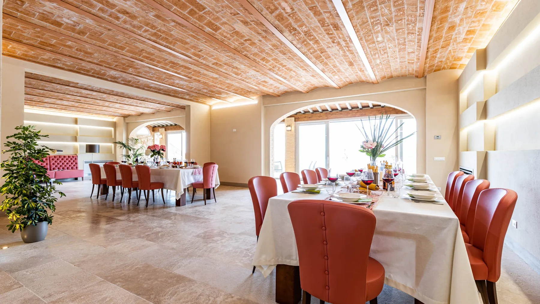A spacious dining room with tables set beneath a brick ceiling.