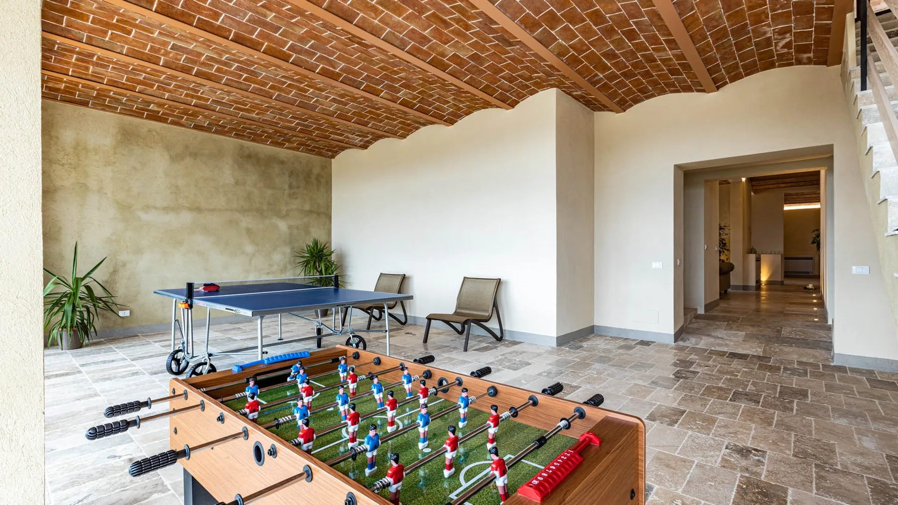 A recreation room with a foosball table and a table tennis table.