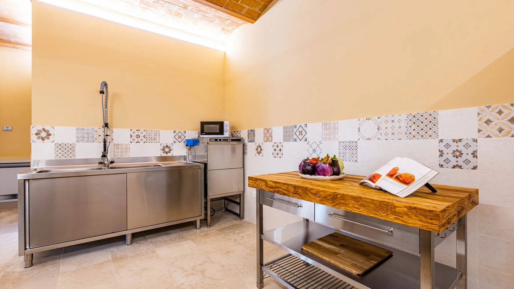 A kitchen prep area with a stainless-steel counter and a wooden worktable.