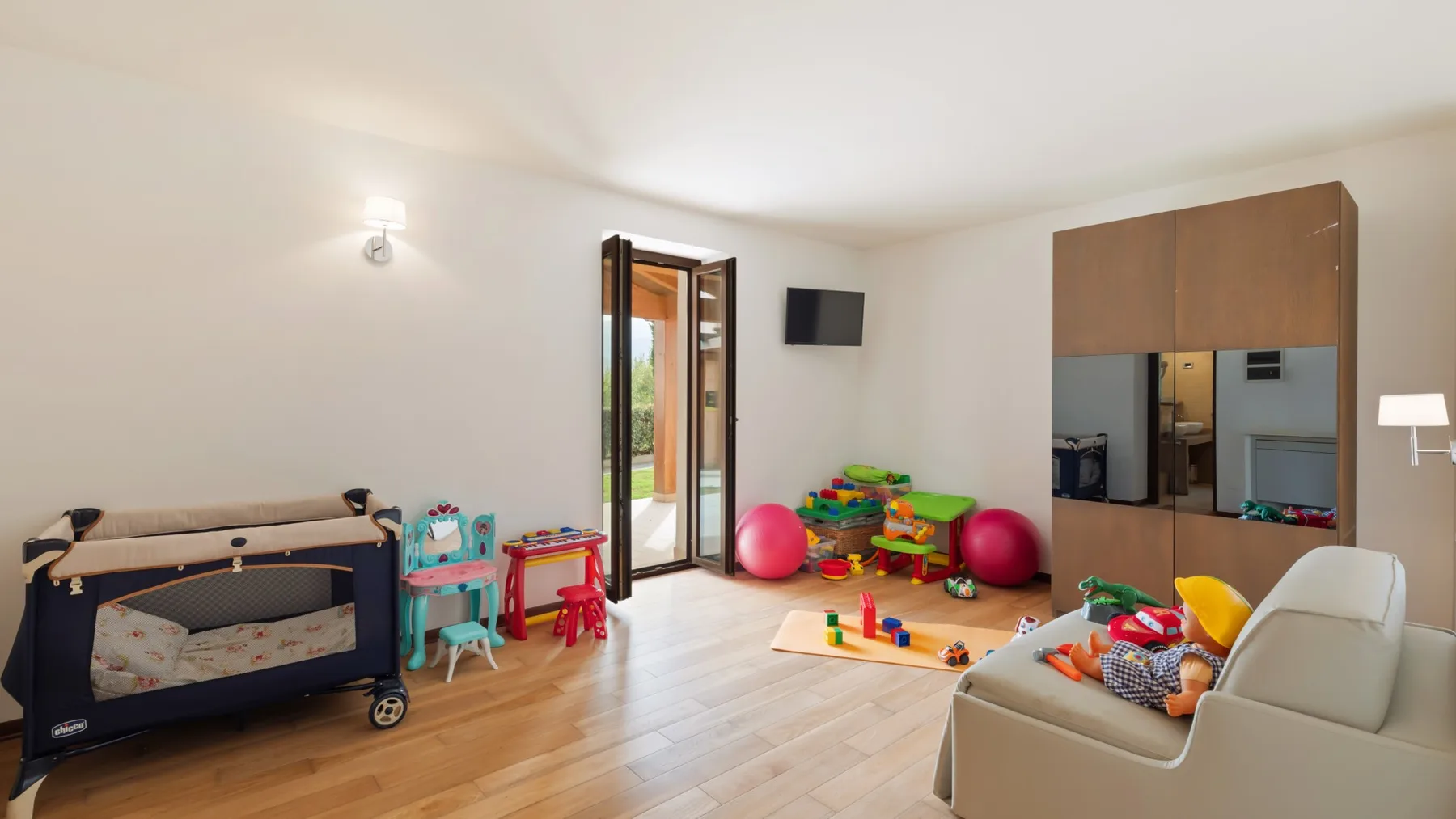 A playroom with colorful toys and a small television mounted on the wall.