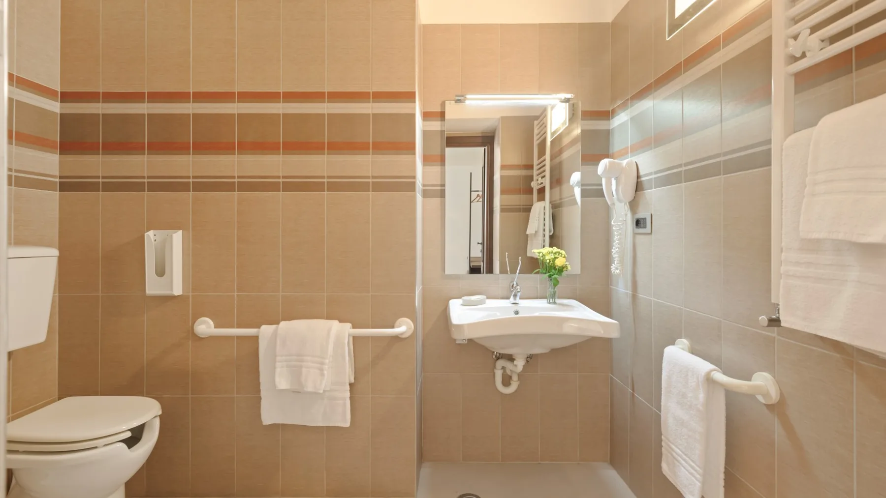 A tiled bathroom with a sink, mirror, and toilet.