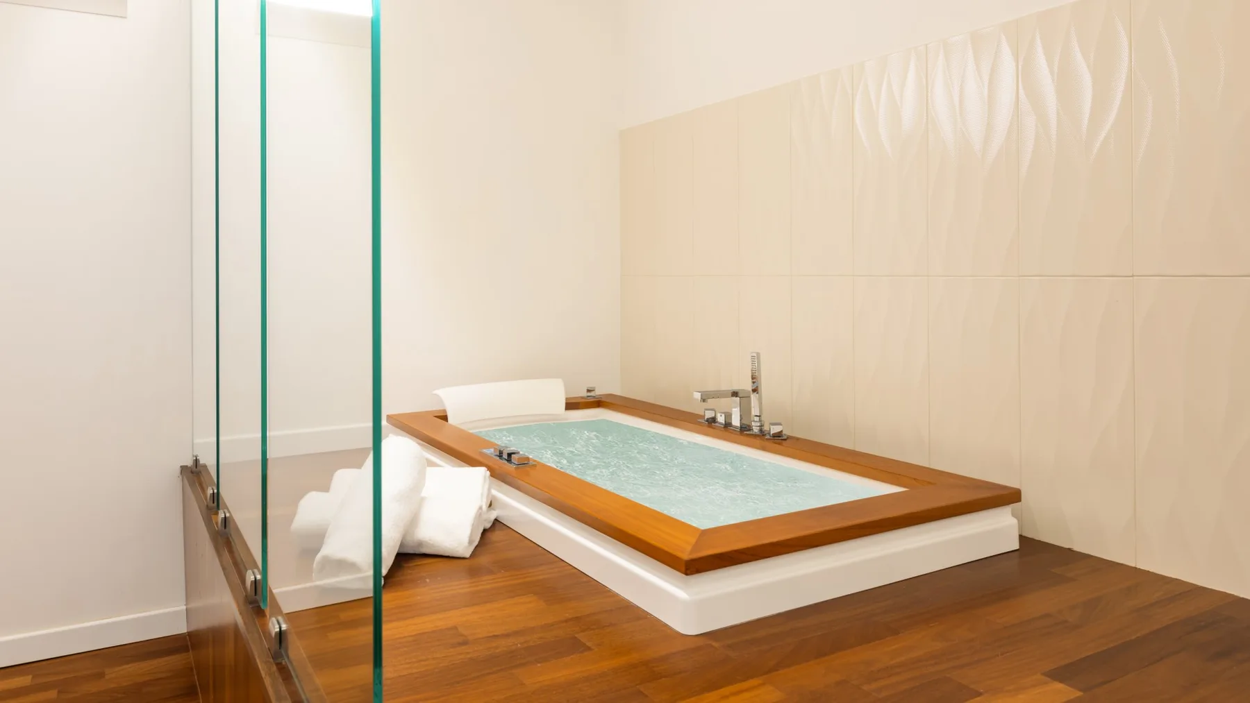 A bathroom features a rectangular soaking tub with water and wooden trim.