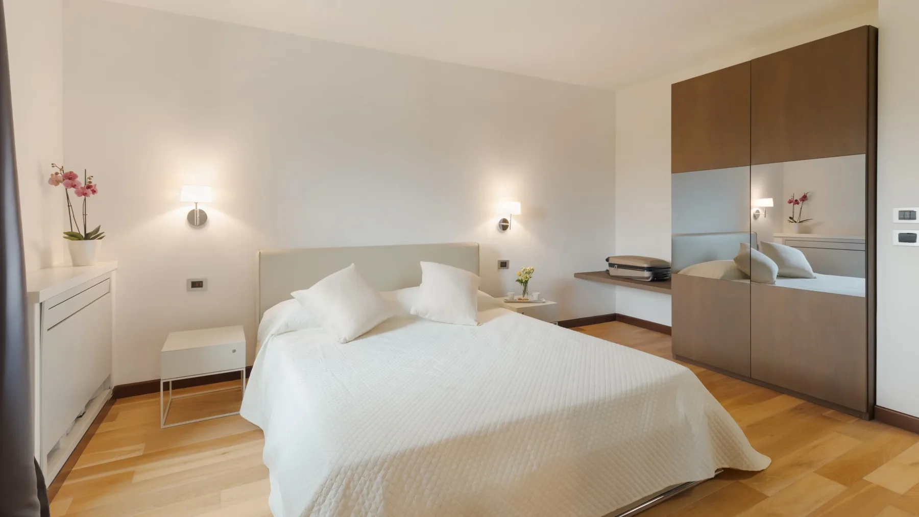 A bright bedroom with a neatly made bed and built-in wardrobes.
