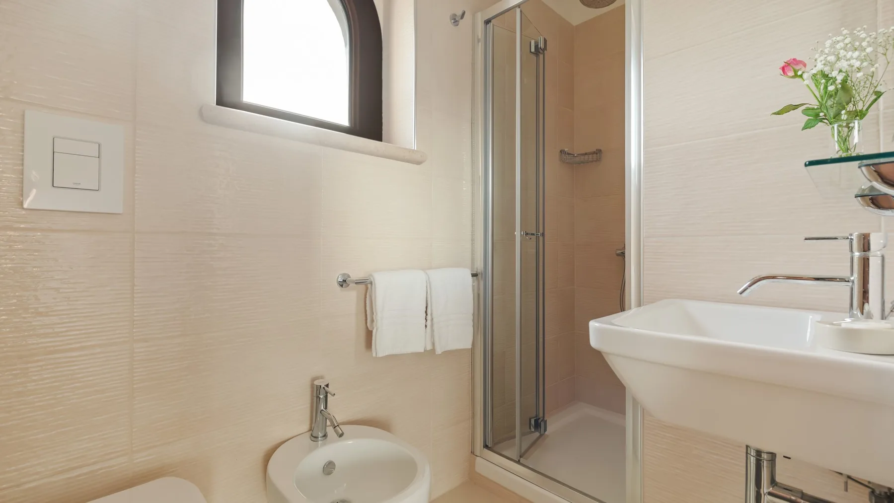 A bright bathroom with a glass shower and a large sink.