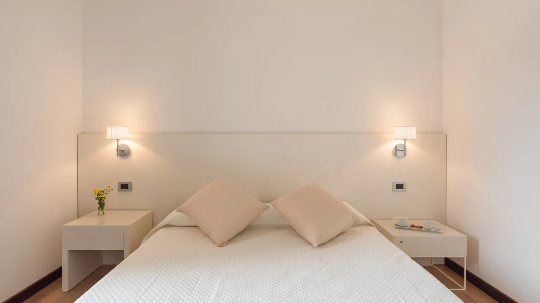 A bedroom with a neatly made bed and matching bedside tables.
