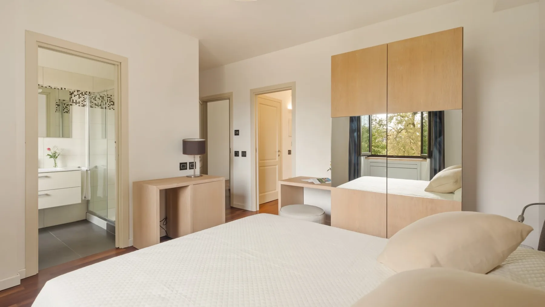 A bright bedroom with a bed, built-in cabinetry, and a window.