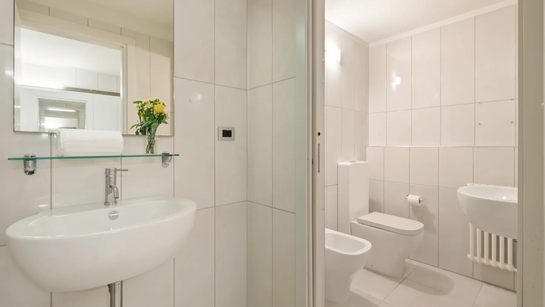 A tiled bathroom with a wall-mounted sink and toilet.