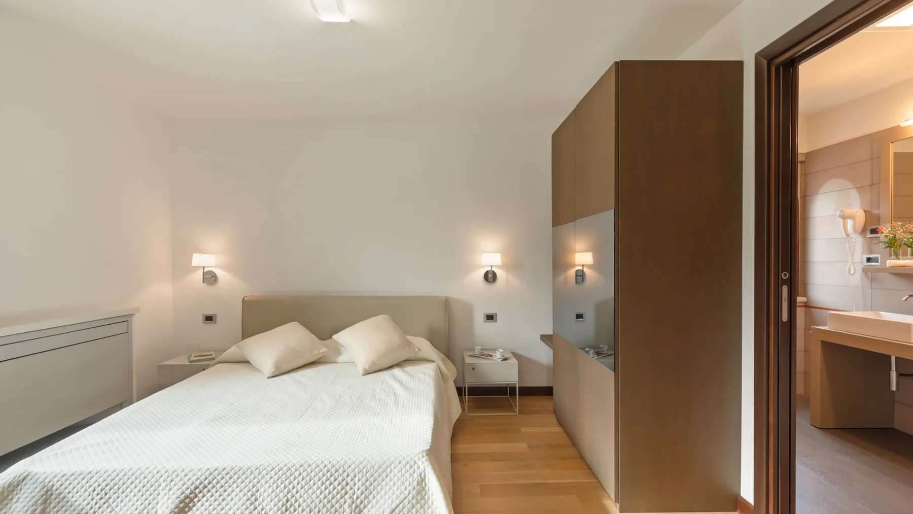 A bedroom with a double bed and a tall wardrobe beside the doorway.
