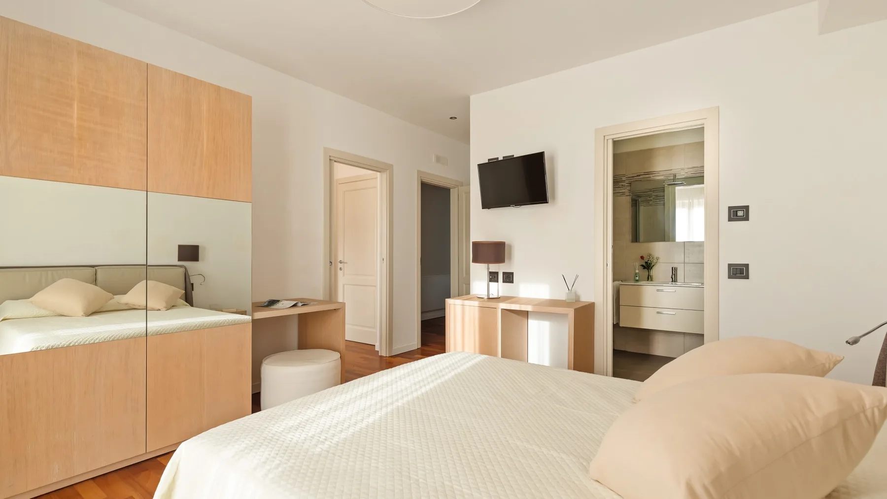 A bright bedroom with a large bed and built-in wooden cabinetry.