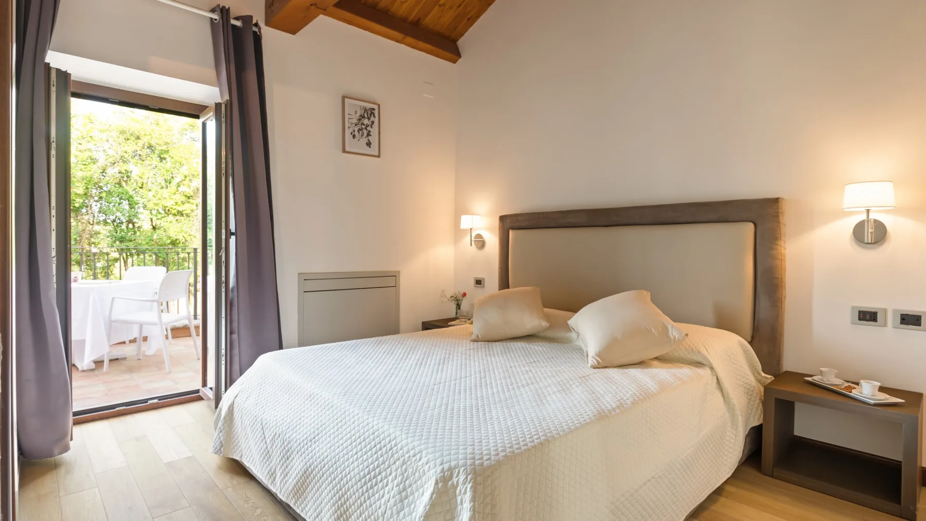 A bedroom with a neatly made bed and an open door to a patio.