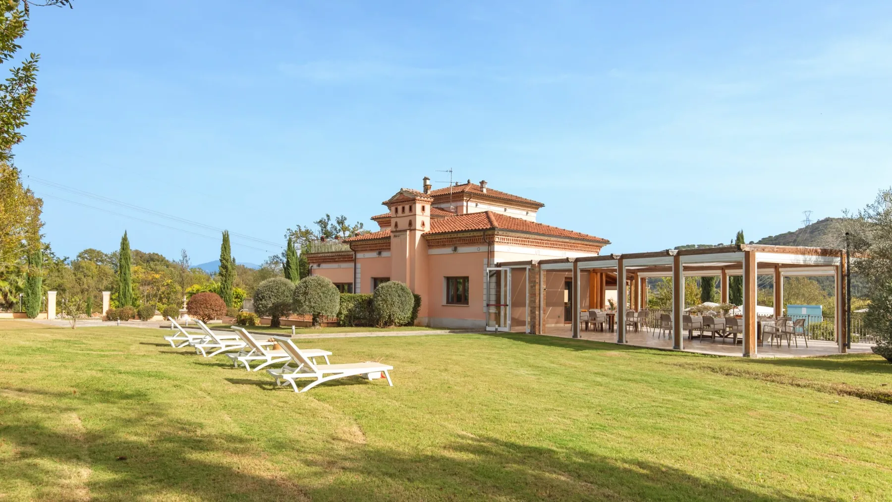 A landscaped lawn with lounge seating in front of a villa and covered patio.