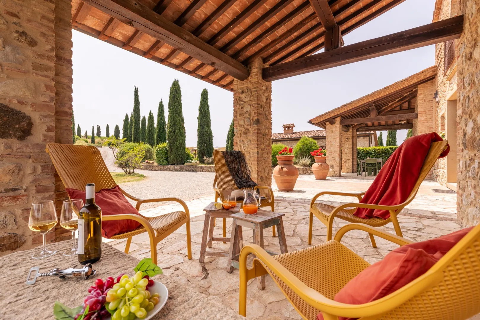 A covered stone patio with outdoor seating and potted plants.