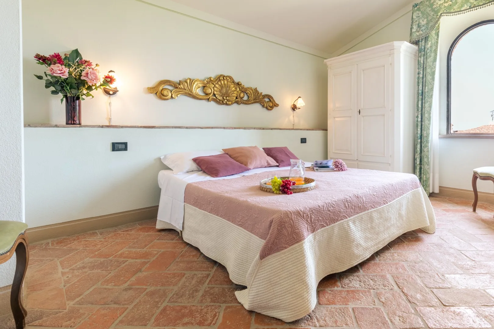 A bedroom with a bed dressed in pink and white bedding.