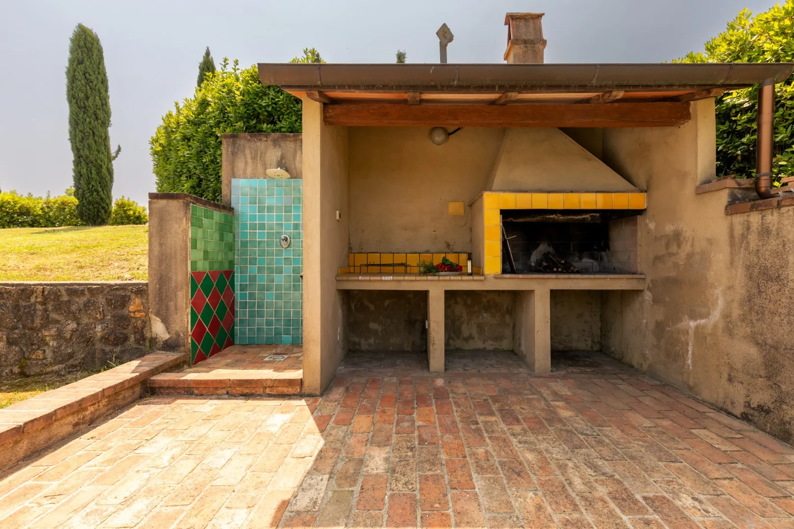An outdoor cooking area with a brick oven and tiled flooring.
