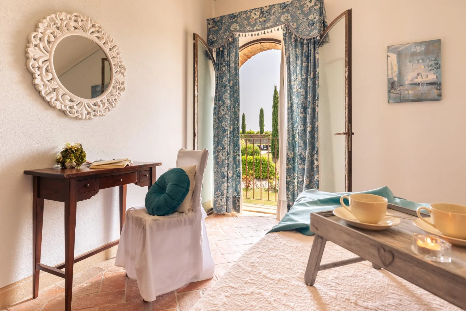 A bright sitting room with a desk, cushioned chair, and open balcony doors.
