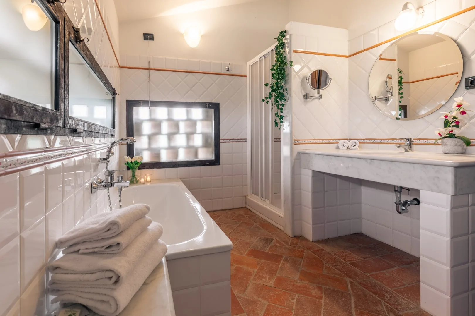 A tiled bathroom with a bathtub, glass shower, and long vanity.
