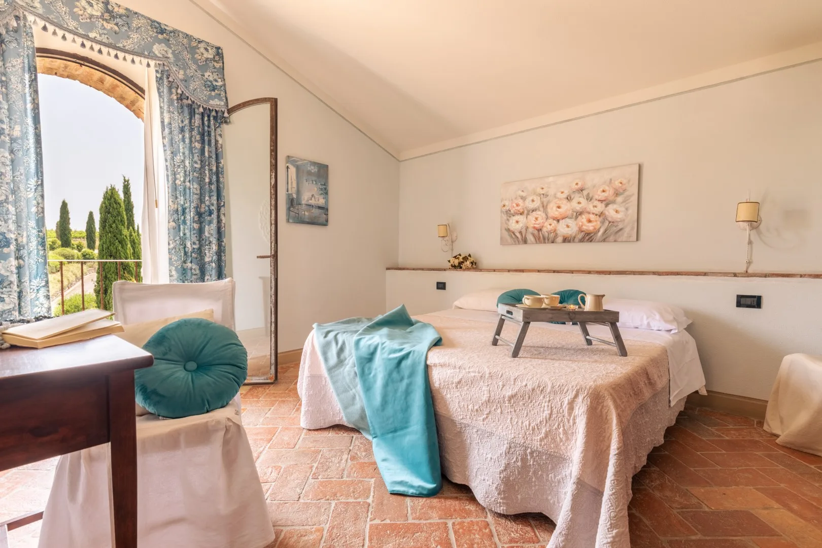 A bedroom with a bed, a small table, and a bright window.