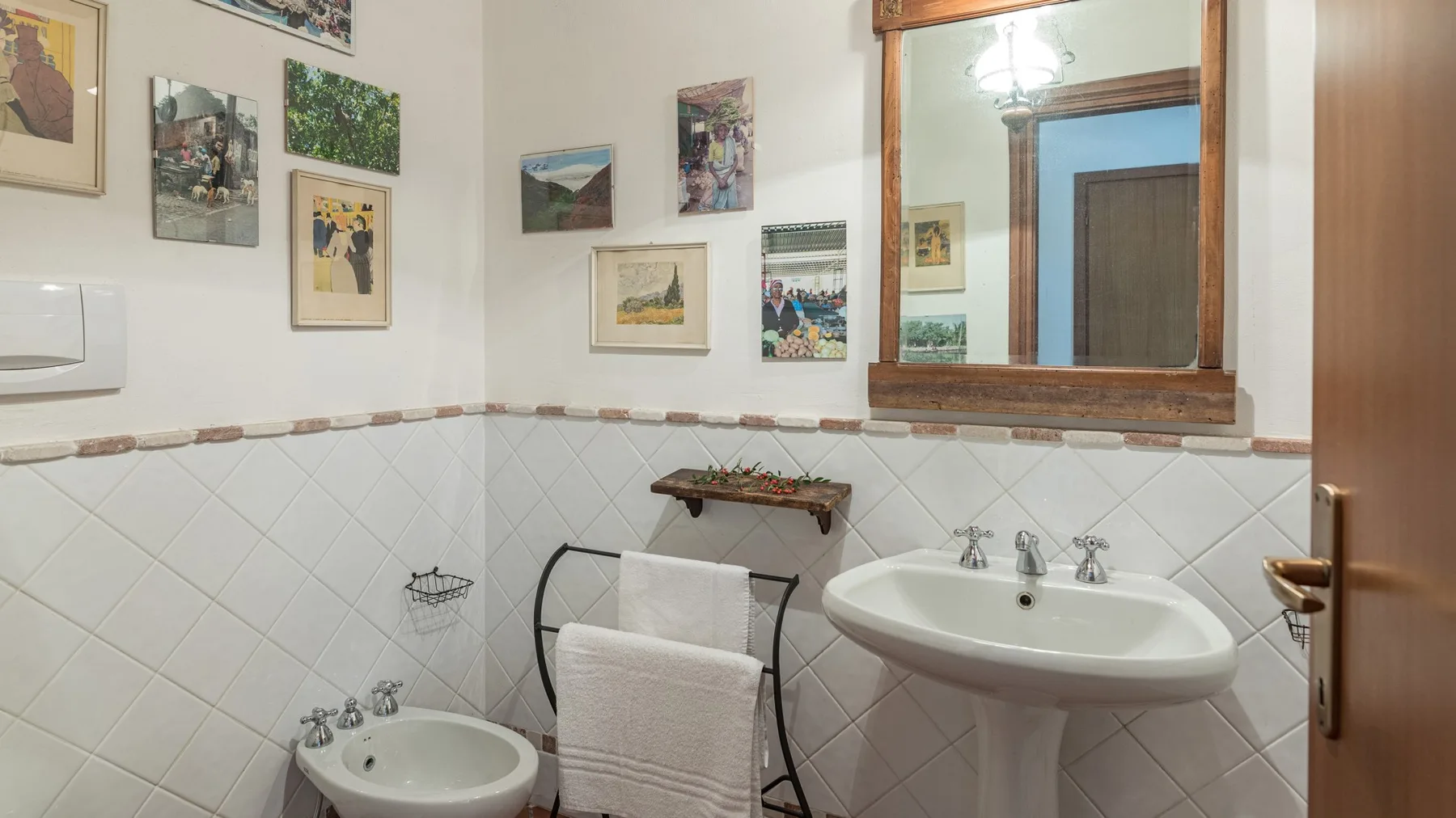 Un baño con lavabo, toallero y cuadros en las paredes.